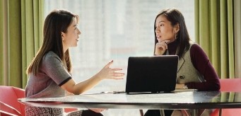 Two individuals having a conversation while sitting at a table.