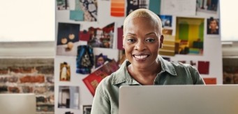 An individual smiling while on their laptop.