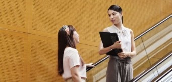Two individuals having a conversation while standing on an escalator.