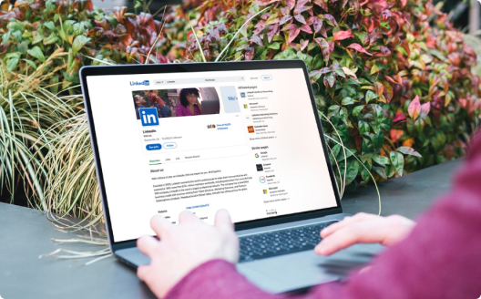 An individual browsing LinkedIn on their laptop outside.